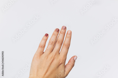Female nails with different pastel colors on white background. Home modern manicure. Female hand raised up. Woman rights