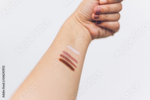Female arm with different pastel colors on skin on white background. Modern makeup colors, home manicure. Female hand raised up