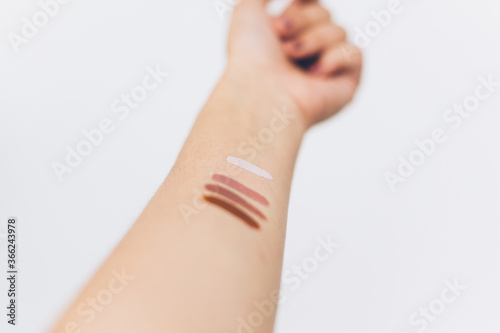 Female arm with different pastel colors on skin on white background. Modern makeup colors  home manicure. Female hand raised up