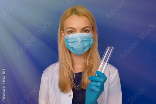 A girl doctor in a medical mask and gloves holding test tubes on a blue background