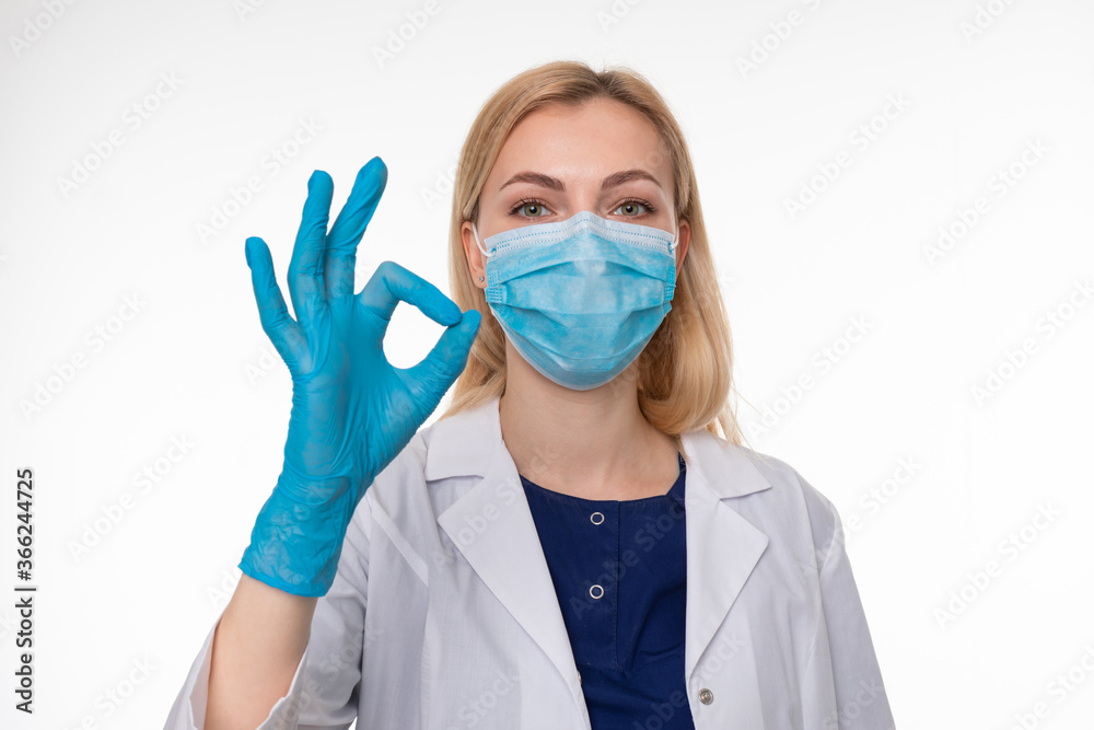 The doctor in a protective mask and gloves gestures ok The doctor in a protective mask and gloves gestures ok