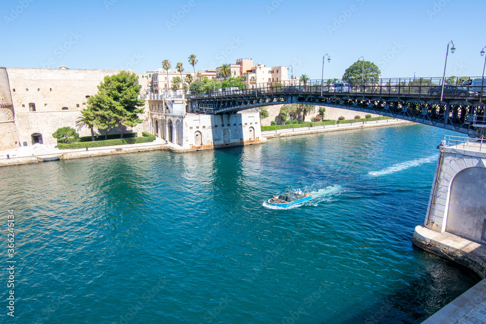 small boat that cross the swing bridge in front of the aragonian castle in taranto on blue sky background