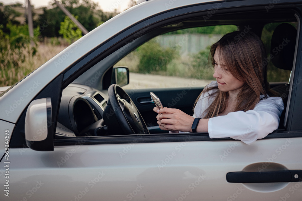 a beautiful young woman driving a grey car.