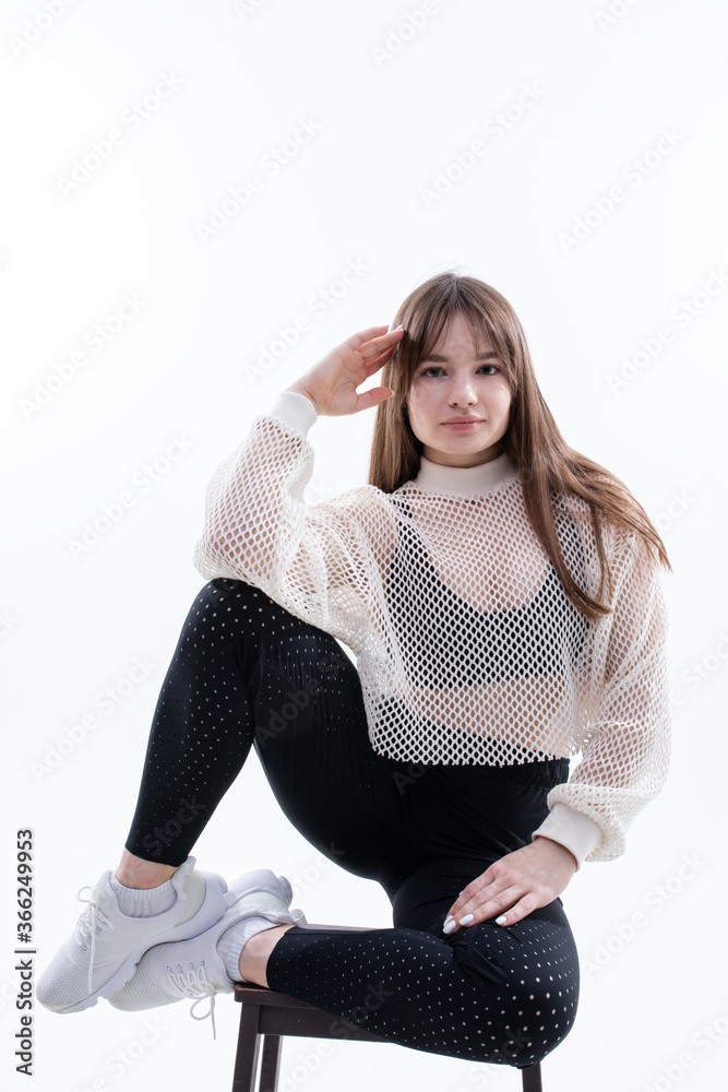 Fototapeta premium A girl in sweatpants, top and jacket poses on a white background. Fashion photography of clothing