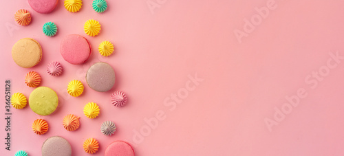 Pile of colorful macaroon cookies on pink background