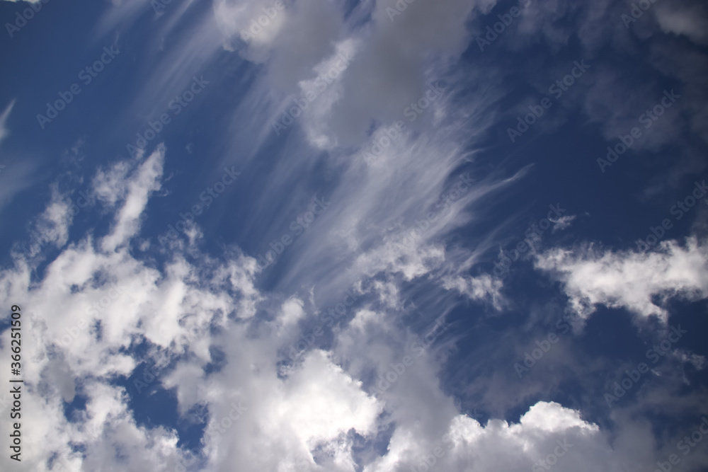 Cumulus and cirrus clouds on a blue sky in sunny weather
