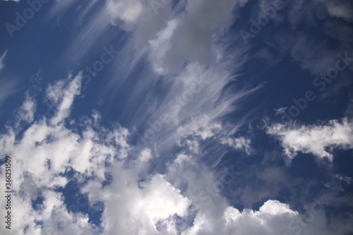 Cumulus and cirrus clouds on a blue sky in sunny weather
