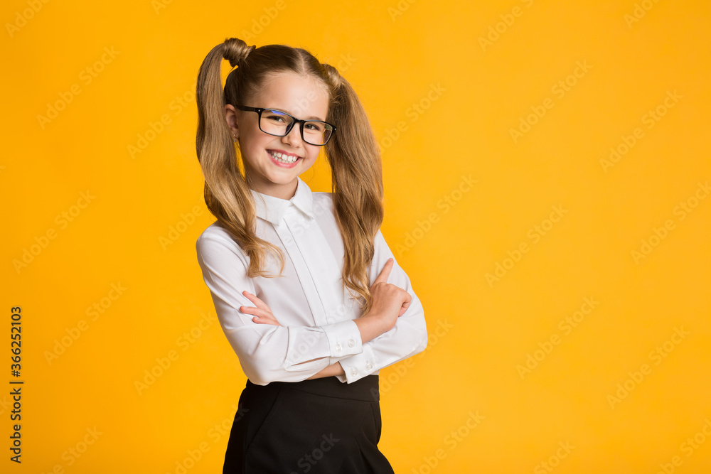 Happy Little Schoolgirl Posing Standing On Yellow Studio Background Happy Little Schoolgirl Posing Standing On Yellow Studio Background