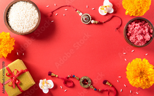 Raksha Bandhan, Indian festival with beautiful Rakhi and  Rice Grains on red background.  A traditional Indian wrist band which is a symbol of love between Sisters and Brothers. photo