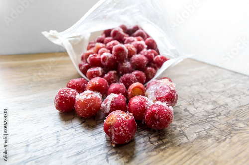Frozen cherries in an open plastic bag in low angle on wooden table