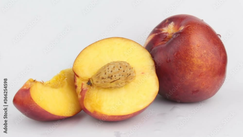 A drop of water flows down a fresh juicy peach. Fresh organic Peach covered with dew drops. Fresh juicy peaches on a white plate.