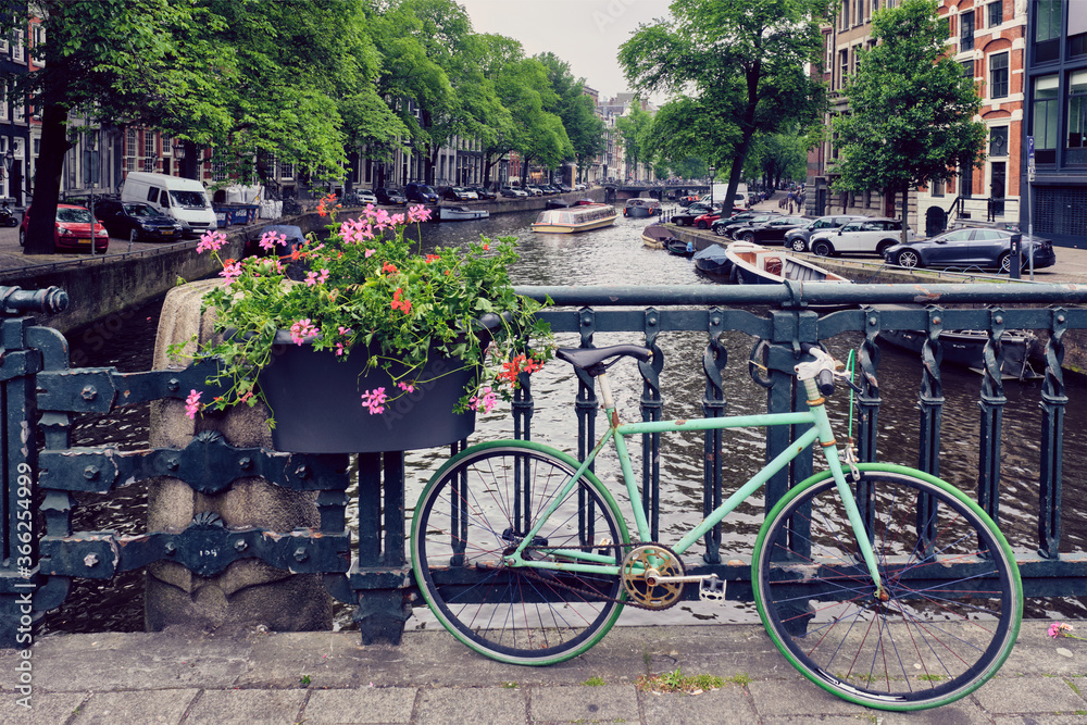 Typical Amsterdam view - Amsterdam canal with boats and parked bicycles on a bridge with flowers. Amsterdam, Netherlands