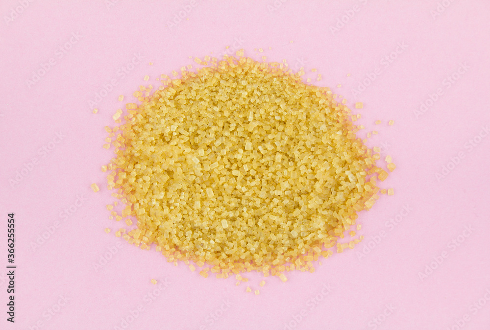 Pile of brown cane sugar on pink background. Top view. Pile of brown cane sugar on pink background. Top view.