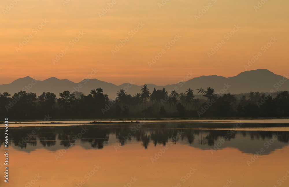Beautiful natural scenery of lake in southeast Asia .Mountain reflextion and shilouettes in the calm water