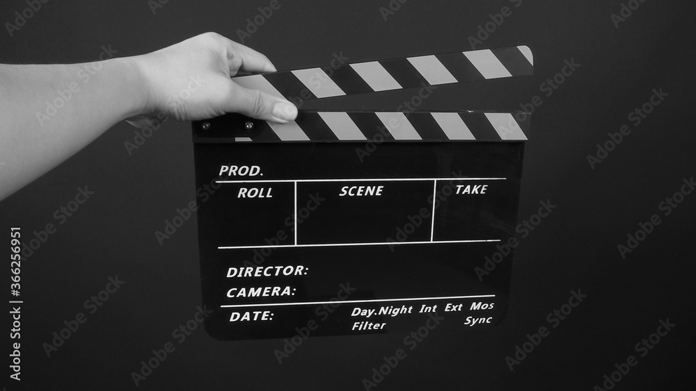 Hand is holding yellow and black color movie slate.It is used in video production and film industry on black background.