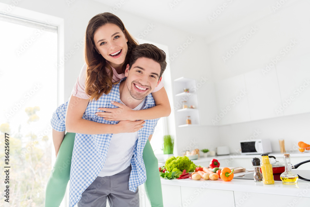 Portrait of his he her she two nice attractive positive cheerful cheery glad spouses preparing homemade dinner having fun guy piggy-backing girl in light white interior kitchen house apartment Portrait of his he her she two nice attractive positive cheerful cheery glad spouses preparing homemade dinner having fun guy piggy-backing girl in light white interior kitchen house apartment