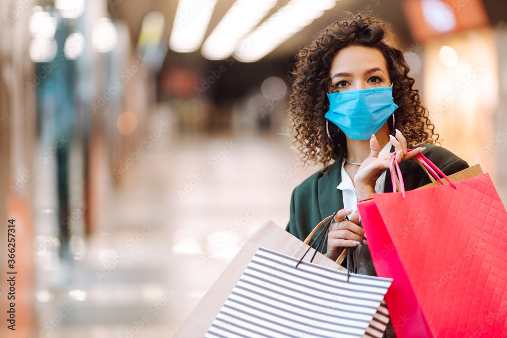 Young woman in medical face mask after shopping during coronavirus pandemic. Covid-2019.