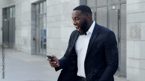 Business man reading good news on cellphone. Entrepreneur celebrating victory photo