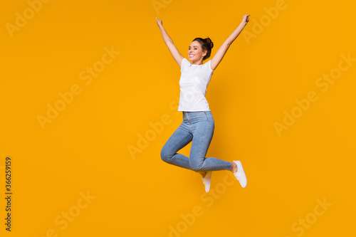 Full length body size view of her she nice-looking attractive lovely cheerful cheery girl jumping rising hands up rejoicing isolated over bright vivid shine vibrant yellow color background © deagreez