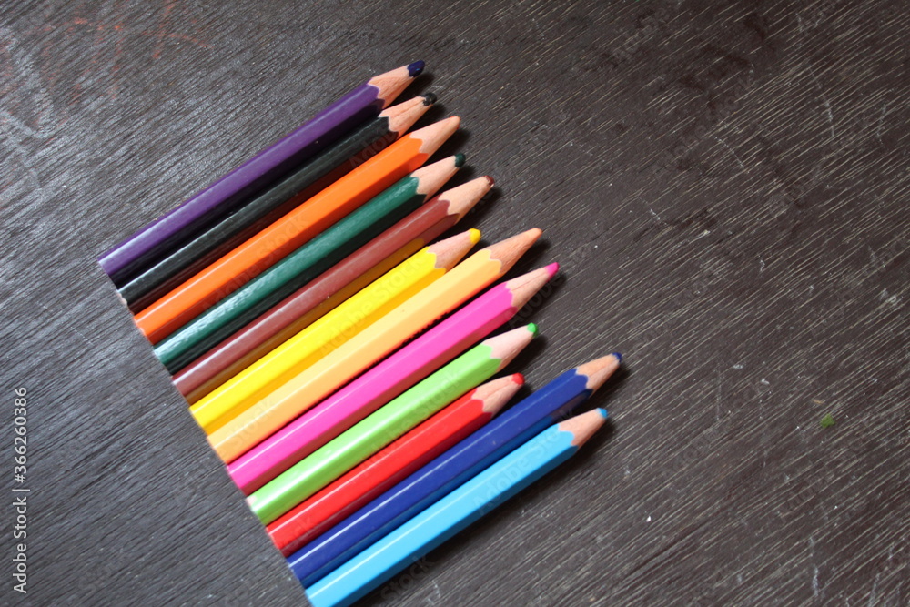 Many colored pencils on a black background. New pencils. Isolated background to insert text, selective focus Many colored pencils on a black background. New pencils. Isolated background to insert text, selective focus