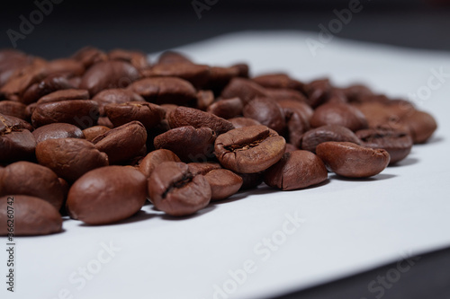 beautiful coffee beans sprinkled on a white table with a black background