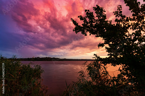 Beautiful sunset on the river with tree branches in the foreground