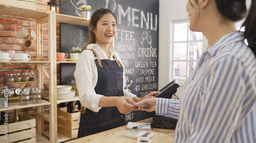 Fotografía businesswoman customer at coffee shop pays smiling waitress with debit card