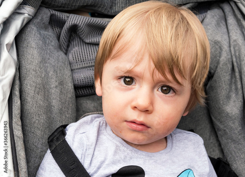 Child boy face close up photo. Little male kid looking at camera. 1 year old caucasian toddler portrait. Young blond lovely baby with surprised brown eyes. Expression of curious and wondering.