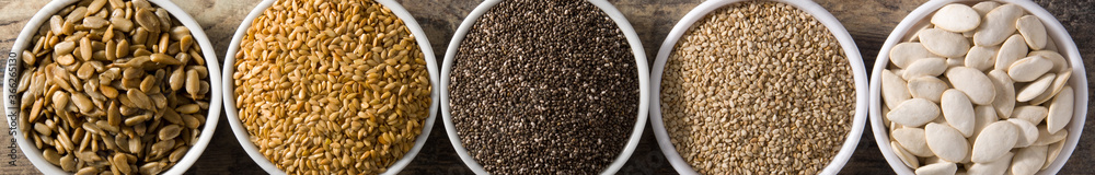 Assortment of different seeds in bowls on wooden table. Panorama view. Top view Assortment of different seeds in bowls on wooden table. Panorama view. Top view