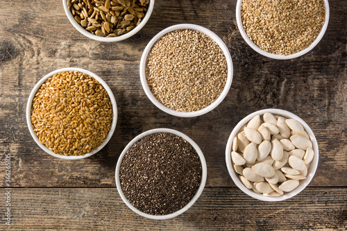 Assortment of different seeds in bowls on wooden table. Top view