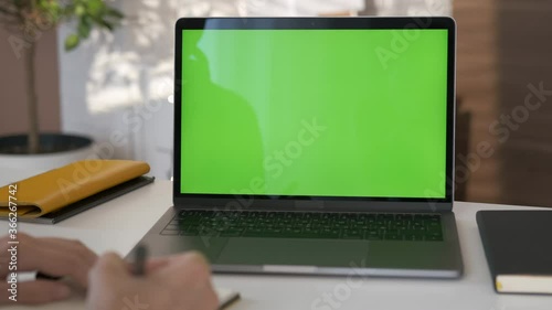 Wallpaper Mural Young student looking at green screen laptop computer in living room watching movie, video content. Over shoulder close up view. Business woman or female freelancer working from home office. Close up Torontodigital.ca