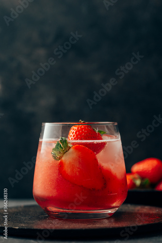 Delicious strawberry cocktail with ice on dark background