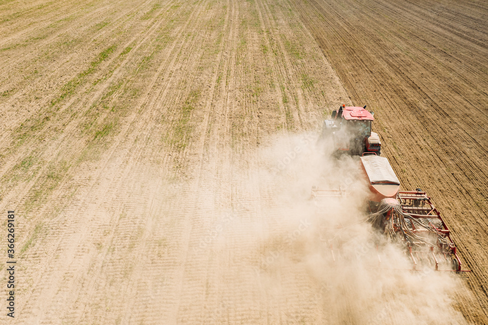 Fototapeta premium Aerial View. Tractor With Seed Drill Machine Sowing The Seeds For Crops In Spring Season. Beginning Of Agricultural Spring Season. Countryside Rural Field Landscape