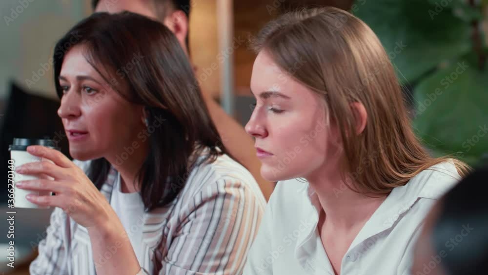 Serious beautiful 20s Caucasian manager business woman sits at team office meeting with middle aged female colleague.