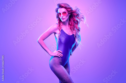 Fashion. Woman in Colorful neon light. Sexy girl in disco bodysuit, makeup dance. Party disco neon nightclub vibes. Fashionable model portrait, creative art neon pink blue light