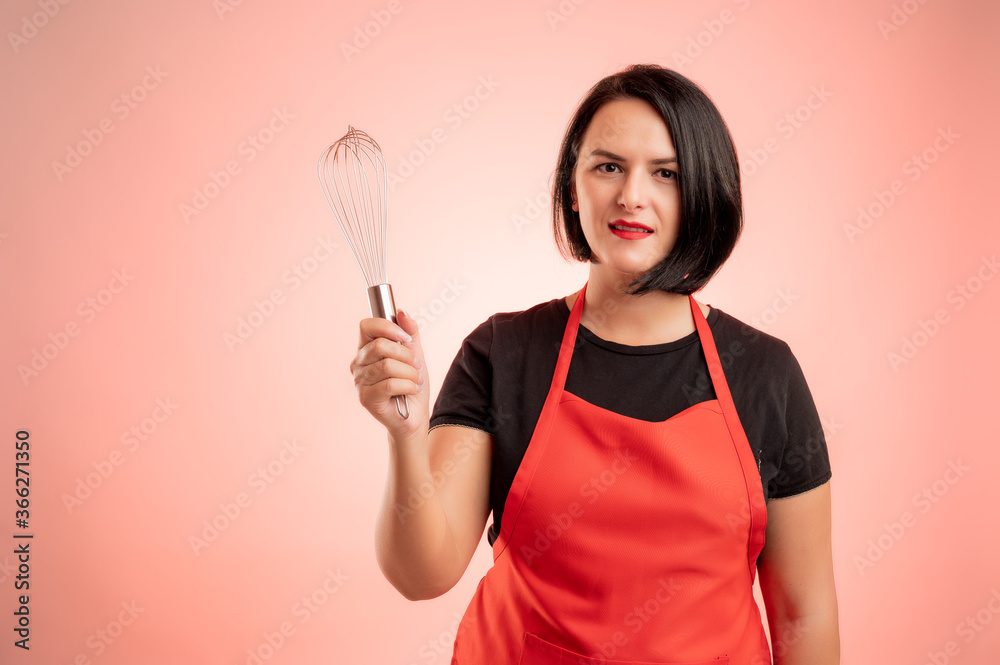 Woman employed at supermarket with red apron and black t-shirt showing metal wire in her hand Woman employed at supermarket with red apron and black t-shirt showing metal wire in her hand