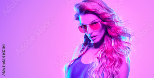 High Fashion. Woman in colorful neon light, make-up. Sexy girl, stylish hair, trendy makeup. Party disco pink purple neon style. Creative art beauty portrait, fashionable model face, make up