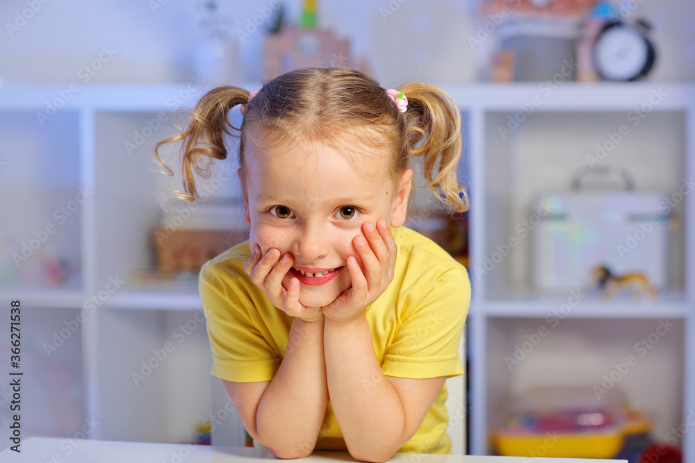cute child a girl in a yellow t shirt sits at a Desk and listens to a lesson cute child a girl in a yellow t shirt sits at a Desk and listens to a lesson