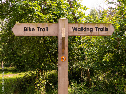 A generic country park signpost in the woodland at Haughmond Hill, Shropshire, UK, showing ‘Bike Trail’ to the left and ‘Walking Trails’ to the right. photo