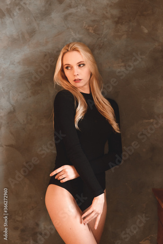 Woman in black bodysuit. girl with wavy hair. Sensual gorgeous young lady in black bodysuit posing in the studio