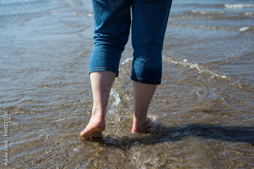 Closeup of feet of woman walking in the water in the sea © pixarno