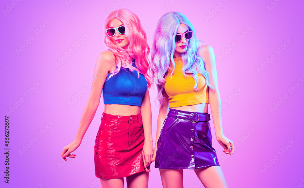 Fashion. Disco party woman have fun dance. Two DJ girl in colorful neon light, sisters. Beautiful model, stylish hair, 80s 90s neon nightclub fashionable style. Pop art. Creative neon light