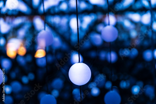 Many illuminated balls hung as abstract blue background
