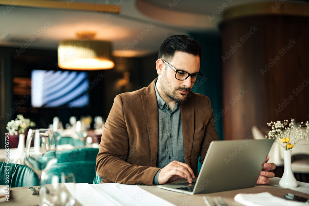 Portrait of a businessman using laptop at restaurant.