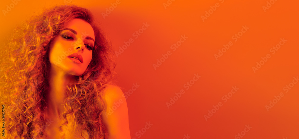 High Fashion. Woman in colorful neon gold light, make-up. Sexy blond girl, stylish curly hair, trendy makeup. Golden neon portrait. Creative beauty, fashionable model face, voluminous hairstyle High Fashion. Woman in colorful neon gold light, make-up. Sexy blond girl, stylish curly hair, trendy makeup. Golden neon portrait. Creative beauty, fashionable model face, voluminous hairstyle