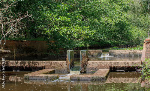 A two stage weir in the Lymington river in Hampshire, UK. Summer sun shines on the weir in low water showing two small water falls