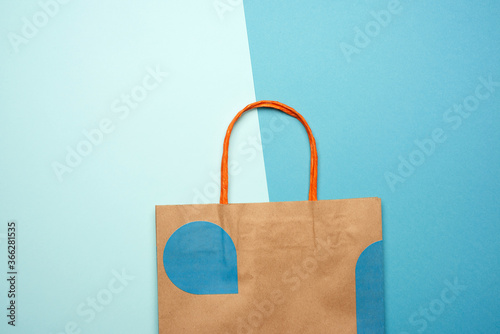 brown paper bag with handles for shopping on a blue background, flat lay