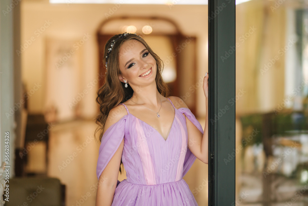 Young woman in beautiful purple dress posing to photographer by the restaurant