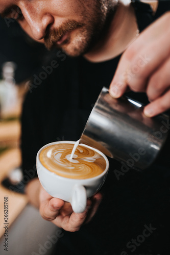 Milk foam from a cappuccinatore to create an art pattern on the top of the coffee - a professional work of a barista