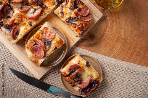 Traditional Italian Focaccia with pepperoni sausage, black olives, parmesan cheese and onion - homemade flat bread Focaccia